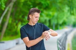 Runner looking at smart watch heart rate monitor having break while running photo