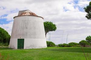 Old white windmill on a green field photo