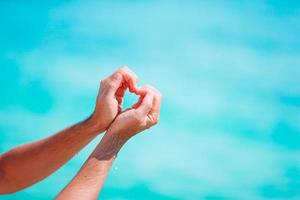 Female hands in the form of heart against the turquoise sea photo