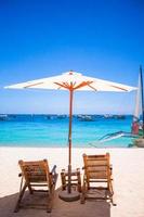 Paradise view of nice tropical empty sandy plage with umbrella and beach chair photo