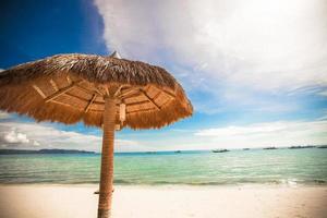 Straw umbrella on a tropical beach photo