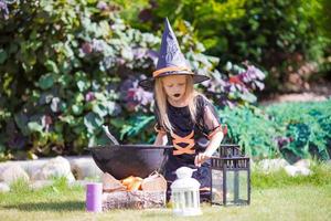 Adorable little girl wearing witch costume casting a spell on Halloween. Trick or treat. photo