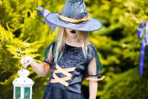 Adorable amasing little girl wearing witch costume on Halloween. Trick or treat. photo