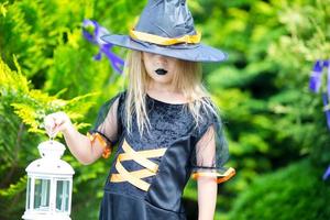 Happy little girl wearing witch costume on Halloween outdoors. Trick or treat. photo