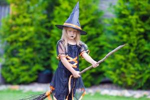 Adorable little girl wearing witch costume on Halloween at autumn day. Trick or treat. photo