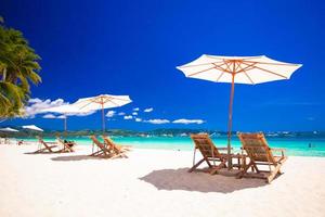 Wooden chairs and umbrellas on white sand beach facing the lagoon photo