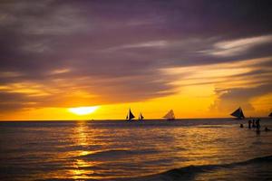 colorido hermoso atardecer con velero en el horizonte en la isla de boracay foto