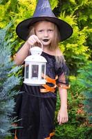 Halloween and adorable little girl with candle dressed as a witch photo
