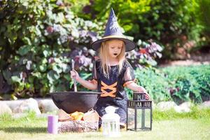 Adorable little girl in witch costume casting a spell on Halloween. Trick or treat. photo