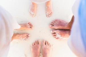 primer plano de los pies de la familia en la playa de arena blanca foto