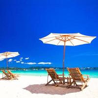 Wooden chairs and umbrellas on white sand beach facing the lagoon photo