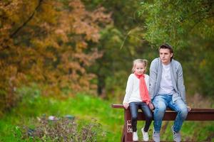 Little girl with happy dad in autumn park outdoors photo