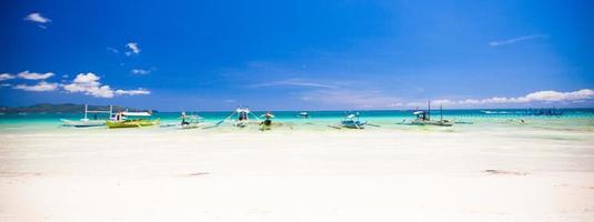 Perfect tropical sandy beach with turquoise water and small sailboats photo