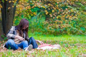 feliz madre con su pequeña hija divirtiéndose en un hermoso día de otoño foto