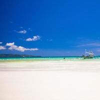 playa de arena tropical perfecta con agua turquesa y pequeños veleros foto