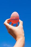 Bright Beautiful pink Easter egg in hand on background of blue sky photo