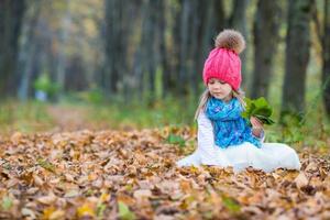 Adorable little girl outdoors at beautiful warm day in autumn park photo