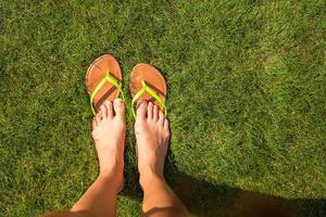 Closeup of woman's legs in slippers on green grass photo