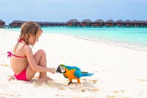 Adorable little girl at beach with big colorful parrot photo