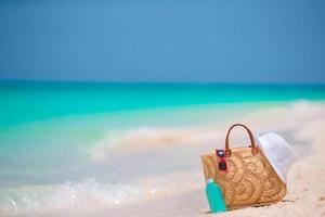 Beach accessories - straw bag, white hat and red sunglasses on the beach photo