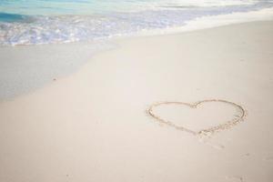 Heart drawn in the sand. Beach background. Top view photo