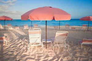 Tropical empty sandy beach with umbrella and chairs photo