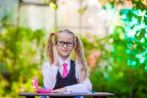 Portrait of happy little school girl in glasses outdoor photo