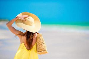 vista trasera de la mujer con sombrero grande durante las vacaciones en la playa tropical foto