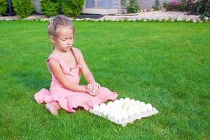 Adorable little girl holding green Easter egg sitting outdoor photo