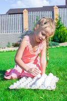 Adorable little girl preparing for Easter with a tray of white eggs photo