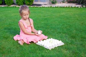 Adorable little girl holding green Easter egg sitting outdoor photo