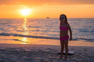 Little adorable girl walking in the sunset on a tropical beach photo