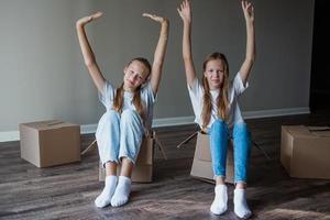 Beautiful young girls moving in new house with cardboard boxes photo