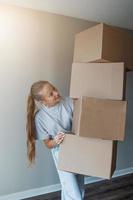 Happy girl moving in new house with cardboard boxes photo