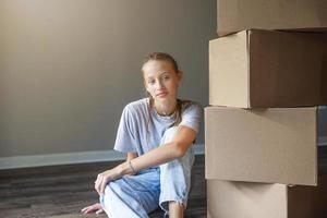 Happy girl moving in new house with cardboard boxes photo