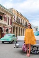 mujer feliz en zona popular en la habana vieja, cuba. joven girltraveler sonriendo feliz fondo coches coloridos foto