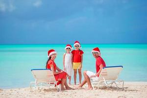 Happy family of four on beach in red Santa hats photo