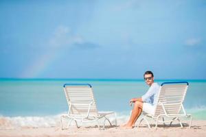 Young man on the beach rest on the chaise-lounge alone photo