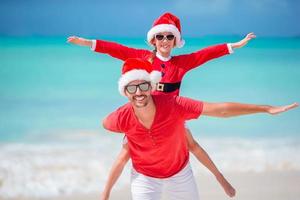 Father and daughter in Santa Hat have fun at tropical beach photo