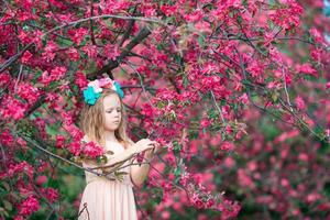 niña hermosa que disfruta del olor en un florido jardín de primavera foto