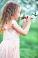 niña hermosa que disfruta del olor en un florido jardín de primavera foto