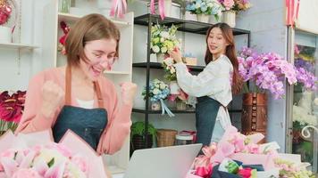 Two young beautiful women florist partners surprise with customer purchase order in e-commerce website, successful business entrepreneur, flower shop happy work, colorful flora bouquet online store. video