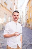 Man tourist with cellphone in Europe street. Caucasian boy looking at camera outdoor photo