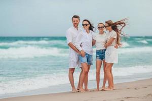 familia de padres jóvenes y dos niños sonriendo y disfrutando del tiempo juntos en las vacaciones en la playa foto
