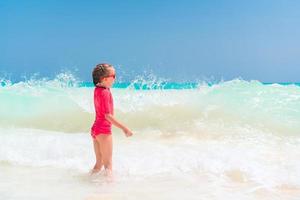 adorable niña en la playa divirtiéndose mucho en el agua foto