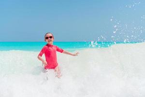 Adorable little girl at beach having a lot of fun in water photo