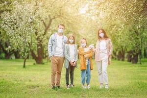 Adorable family in blooming cherry garden in masks photo