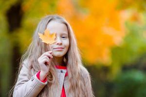 adorable niña al aire libre en un hermoso día cálido en el parque de otoño con hojas amarillas en otoño foto