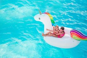 Adorable little girls at swimming pool having fun during summer vacation photo