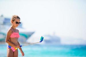 Little girl taking selfie by her smartphone on the beach. photo